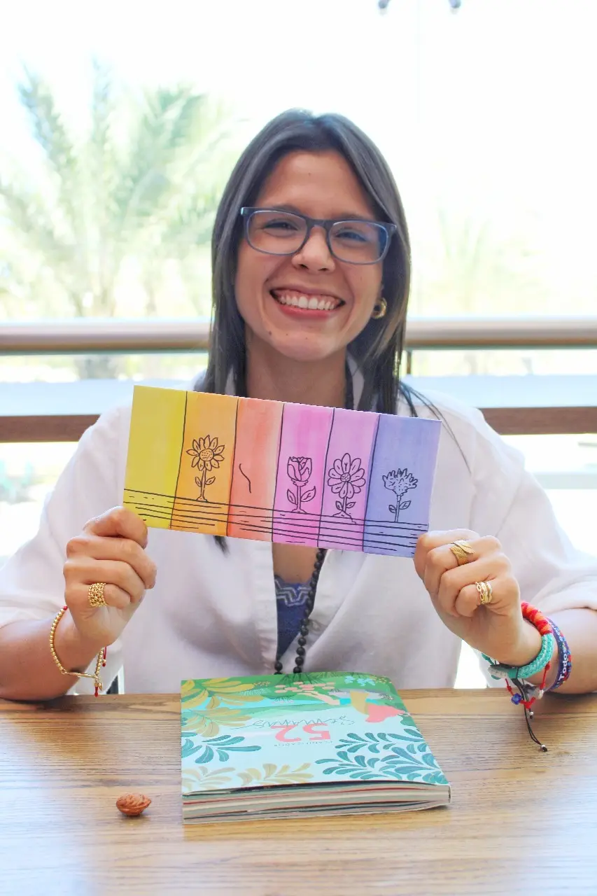 Gaby sostiene tarjetas ilustradas con flores en distintas etapas